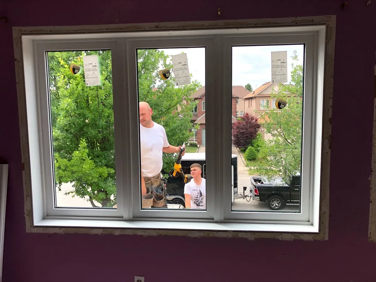 Installer fitting a new vinyl window into a prepared opening